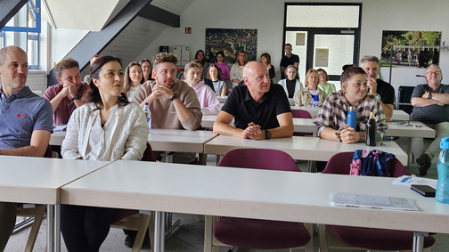 Mehrere Personen sitzen an Tischen in einem Saal