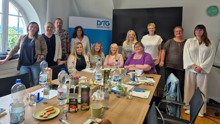 Gruppenfoto stehend hinter einem großen Tagungs-Tisch