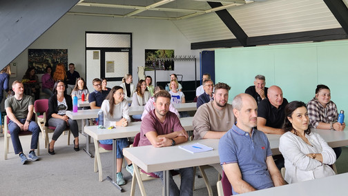 Mehrere Personen sitzen an Tischen in einem Saal