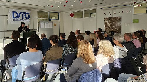 Zuhörerinnen und Zuhörer in Reihenbestuhlung und vorne die Referentin